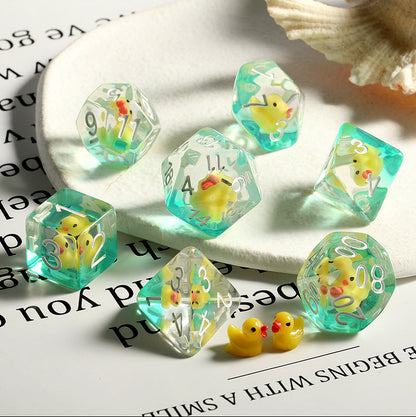 Transparent dice with small rubber ducks inside, placed on a white surface.