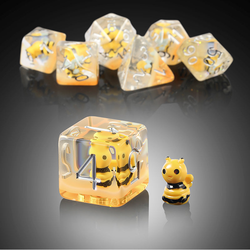 Clear dice with figures with small yellow bee characters inside on a light gray surface.